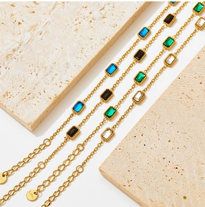Macro detail of gold stainless steel bracelets with blue, green and black cubic zirconia stones