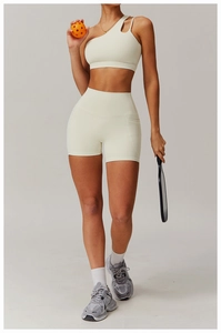 Detail view of one-shoulder sports bra and high-waist shorts in creamy white matte fabric