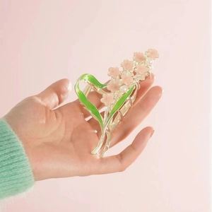 Close-up of pink flower hair claw clip with green leaves and elegant pearl accents