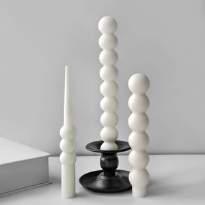 Minimalist stack of white spherical wax candles on elegant black metal candlesticks