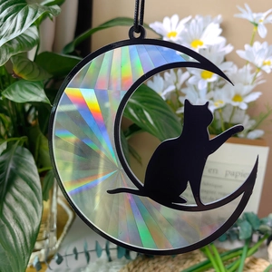 Macro shot of iridescent moon and black cat suncatcher with colorful prism texture