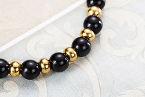 Vue macro des perles noires et sphères dorées sur un fond à motifs de style rétro