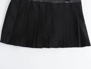 Detail shot of black pleated skirt featuring high-quality faux leather texture and seams