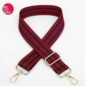 Dettaglio della tracolla larga in tessuto motivo chevron rosso e nero con ganci dorati
