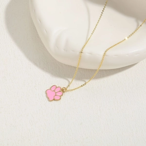 Close-up of pink cat paw pendant necklace with gold chain on white background