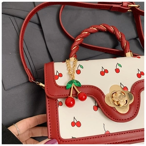 Détails du sac à motif cerises avec poignée tressée et fermoir fleur dorée
