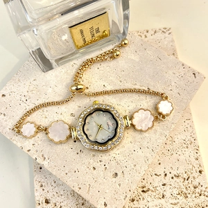 Detailed close-up of a gold floral watch with a mother of pearl dial and rhinestone bezel