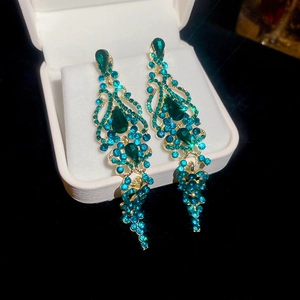 Detail of drop tassel earrings with turquoise crystals in a white jewelry gift box