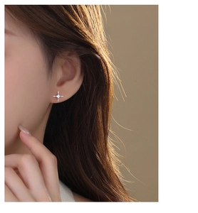 Close-up of a sparkling silver star-shaped stud earring worn on a woman's ear