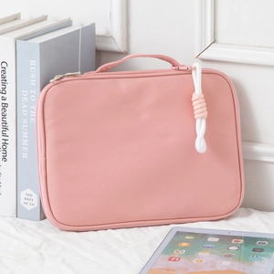 Pink protective laptop sleeve with carry handle and woven charm shown in home setting