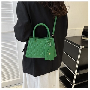 Detail of vibrant green embossed crossbody bag with detachable mini envelope pouch