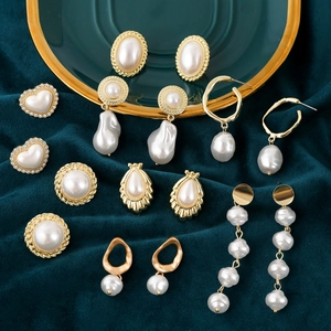 Collection of vintage pearl earrings including heart-shaped and baroque drop styles on velvet