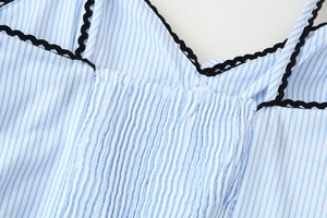 Detail eines blau-weiß gestreiften Kleides mit schwarzer Häkelspitze und geraffter Brust