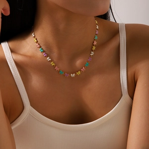 Gros plan d'un collier doré avec des pendentifs papillons émaillés sur un mannequin