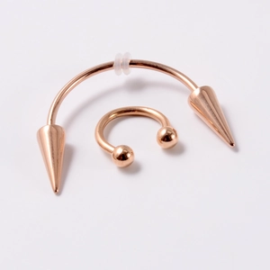 Detailed view of rose gold stainless steel horseshoe ring and spiked curved barbell