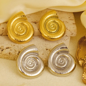 Macro detail of spiral shell stud earrings in gold and silver finish on stone texture