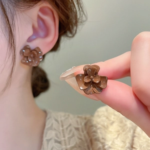 Macro shot of brown 3D flower earrings with glossy finish and silver needle posts