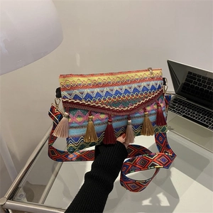 Close-up of bohemian woven crossbody bag featuring colorful tassels and wide strap