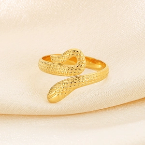 Close-up of golden snake ring with scales texture on light beige silk background