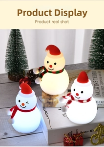 Three cute snowman night lights with festive hats and scarves on a wooden table