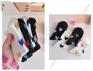 Detail of crew socks featuring colorful heart patterns in black and white cotton fabric