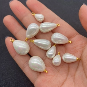 Water-drop imitation pearl pendants with gold metal rings displayed in hand for scale