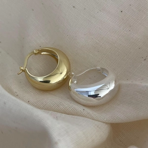 Close-up of thick 925 sterling silver hoop earrings in gold and silver mirror finish