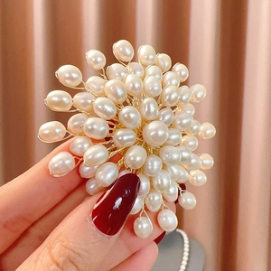 Detailed close-up of a handcrafted white freshwater pearl flower brooch being held