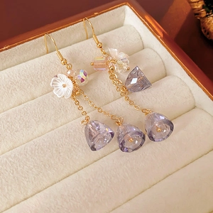 Detail of gold chain earrings with purple crystal drop and white shell flower charms