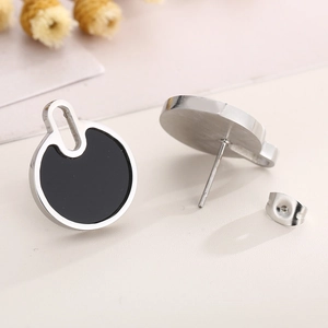 Macro shot of minimalist black and silver titanium steel stud earrings with secure backs
