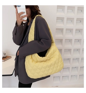 Detail view of bright yellow quilted puffer tote bag with soft padded shoulder strap