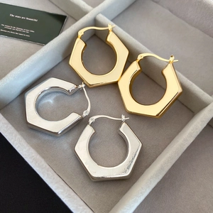 Detailed view of geometric hexagonal hoop earrings in polished gold and silver finishes