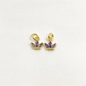 Close-up of golden crown pendants with purple zircon stones on white background