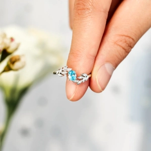 Close-up of s925 silver leaf ring featuring an oval light blue gemstone and pavé diamonds