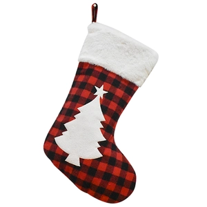 Detail of red and black buffalo plaid Christmas stocking with white fur trim and tree appliqué