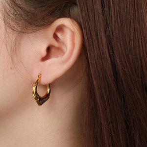 Close-up of golden stainless steel geometric hoop earrings with vintage textured surface