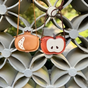 Detail of creative pomegranate and apple shaped leather mini bags with soft straps