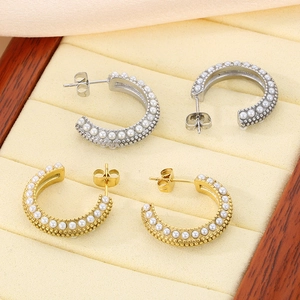 Detail of vintage C-shape pearl earrings in gold and silver finish in a jewelry box
