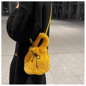 Close-up of a yellow plush bucket bag with black drawstring bow and metal hardware