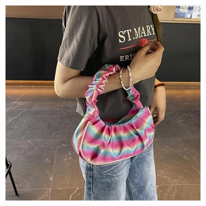 Detail of pleated shoulder bag with vibrant rainbow gradient and satin finish texture