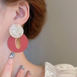 Detail of geometric resin earrings with white shell pattern and red matte round pendants