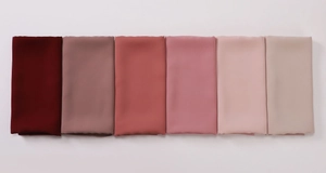 Detailed color gradient showing six folded silk-like hijabs from burgundy to beige tones