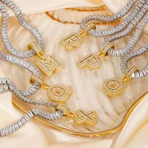 Elegant gold letter pendants with baguette-cut silver chains on beige silk