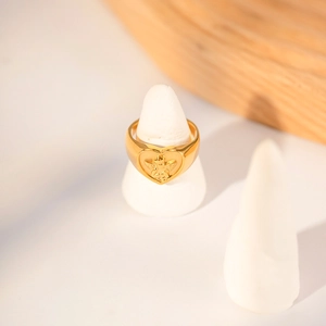 Macro shot of gold heart ring featuring an angel relief on white jewelry cone stand
