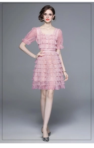 Détail d'une robe en dentelle rose clair avec encolure carrée et manches bouffantes