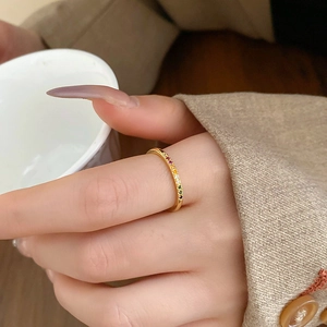 Close-up of golden ring set with colorful rainbow zircons on a model's hand