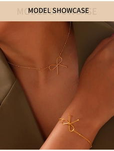 Golden bow necklace and bracelet set displayed on a model in a green suit