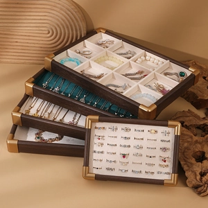 Detail of walnut wood jewelry tray with gold metal corners and velvet ring slots