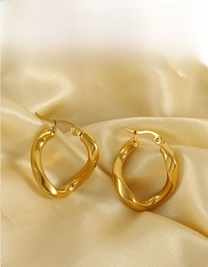 Close-up of irregular 18k gold-plated hoop earrings on a luxury satin background