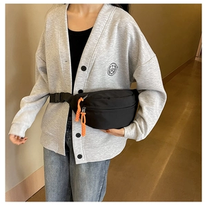 Detailed view of black canvas crescent bag with vibrant orange rope zipper pulls